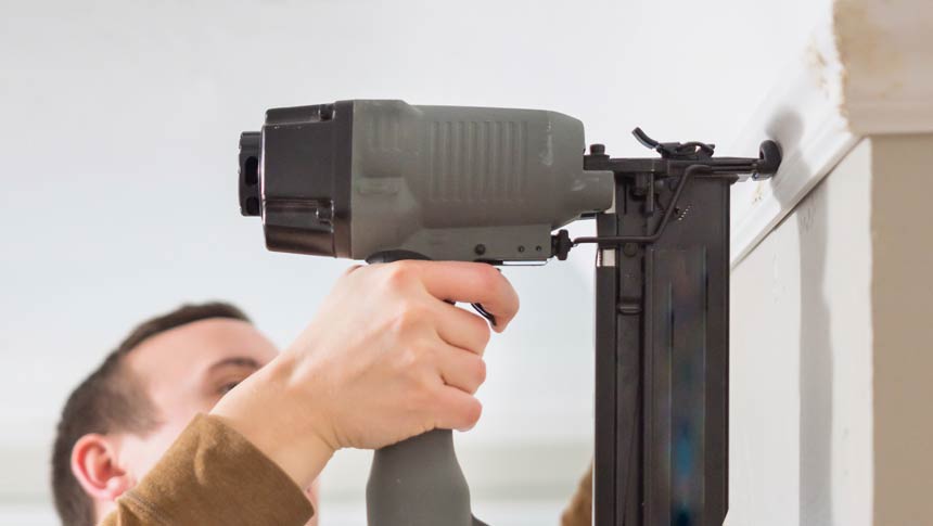 Carpenter works with cordless finish nailer